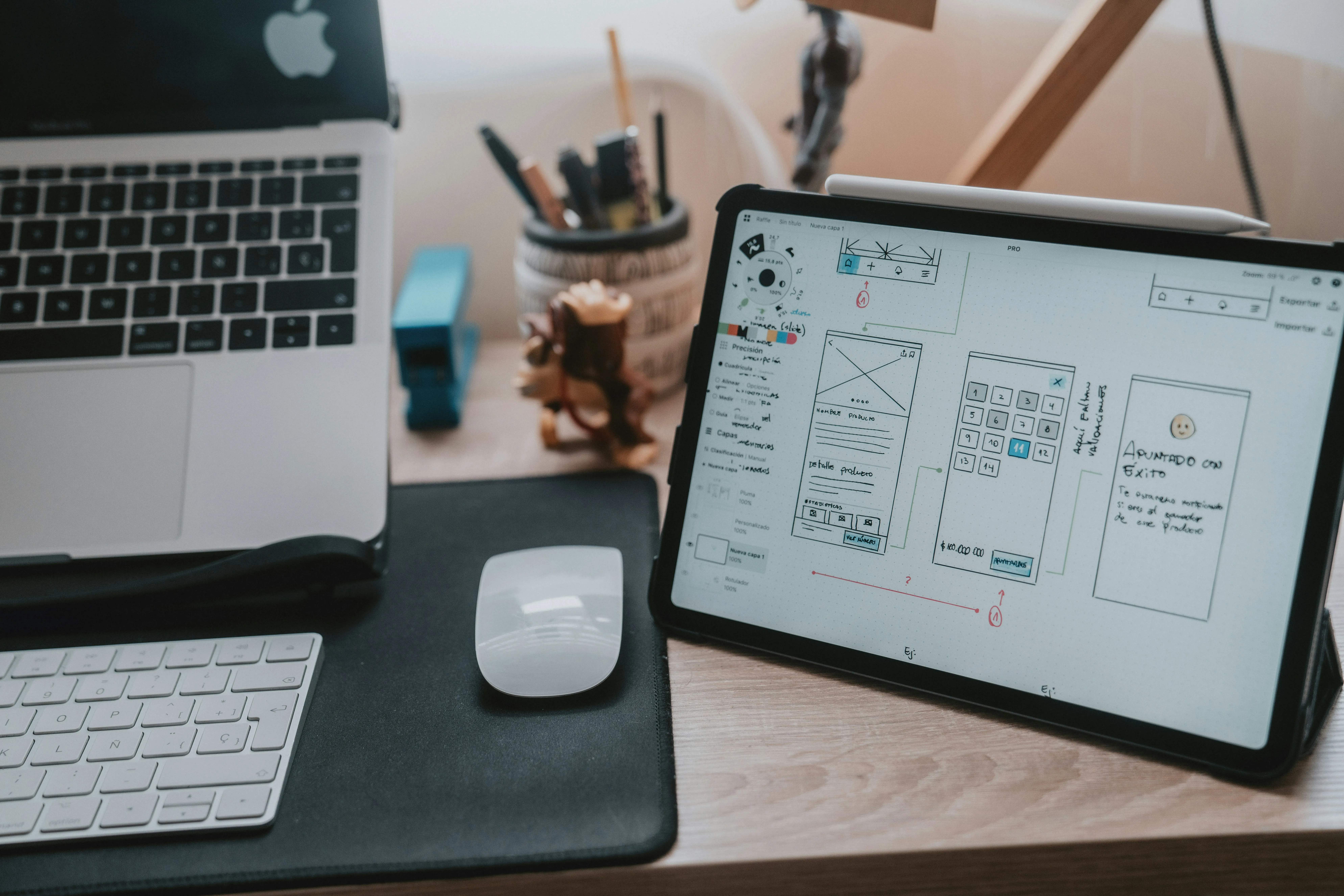 Un laptop MacBook deschis și o tabletă afișând un wireframe de design UI/UX, simbolizând procesul de web design și dezvoltare, cu accent pe echilibrul dintre calitate și cost.