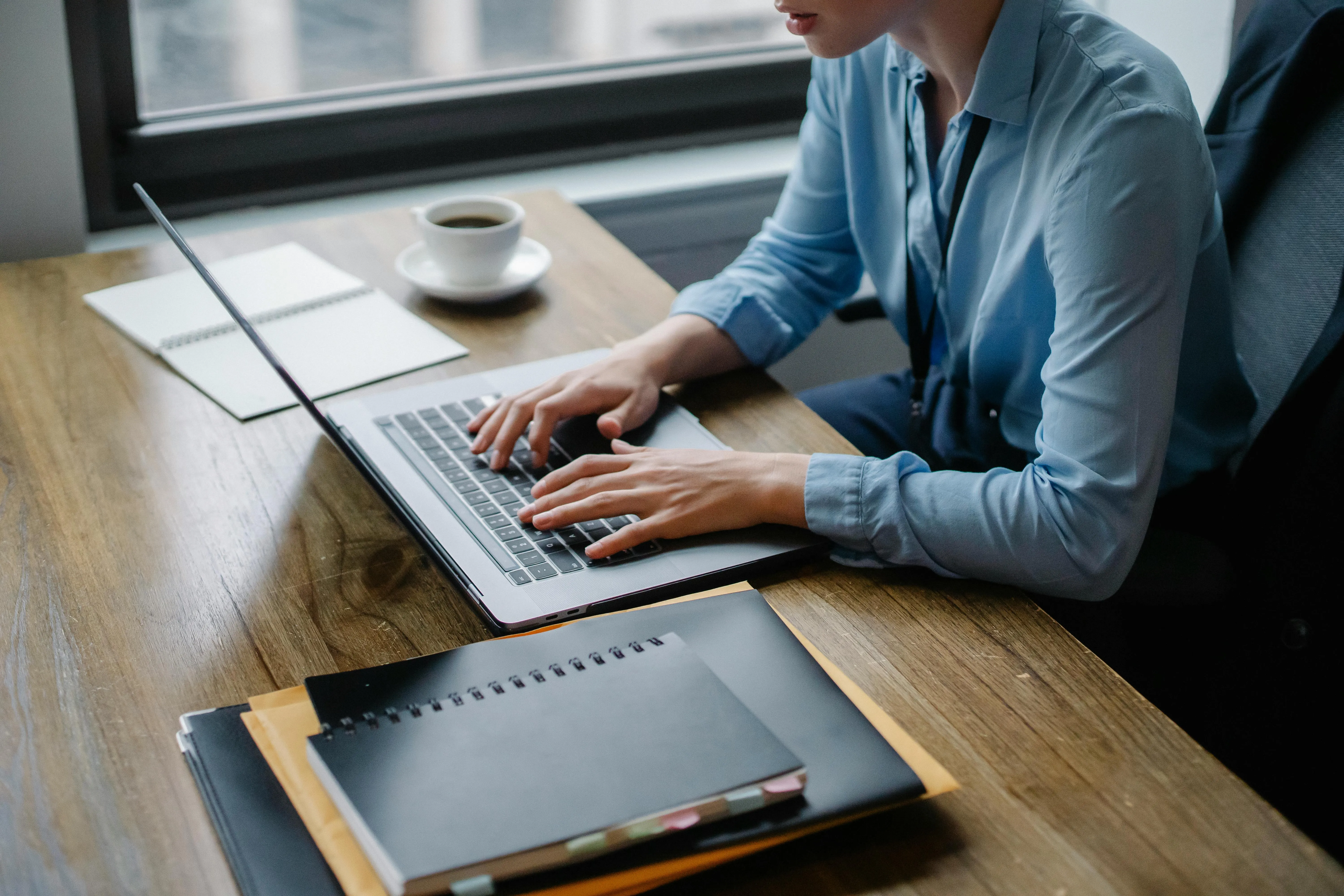 O persoană care scrie la un laptop, cu o ceașcă de cafea lângă, simbolizând procesul de a scrie conținut pentru un site web.
