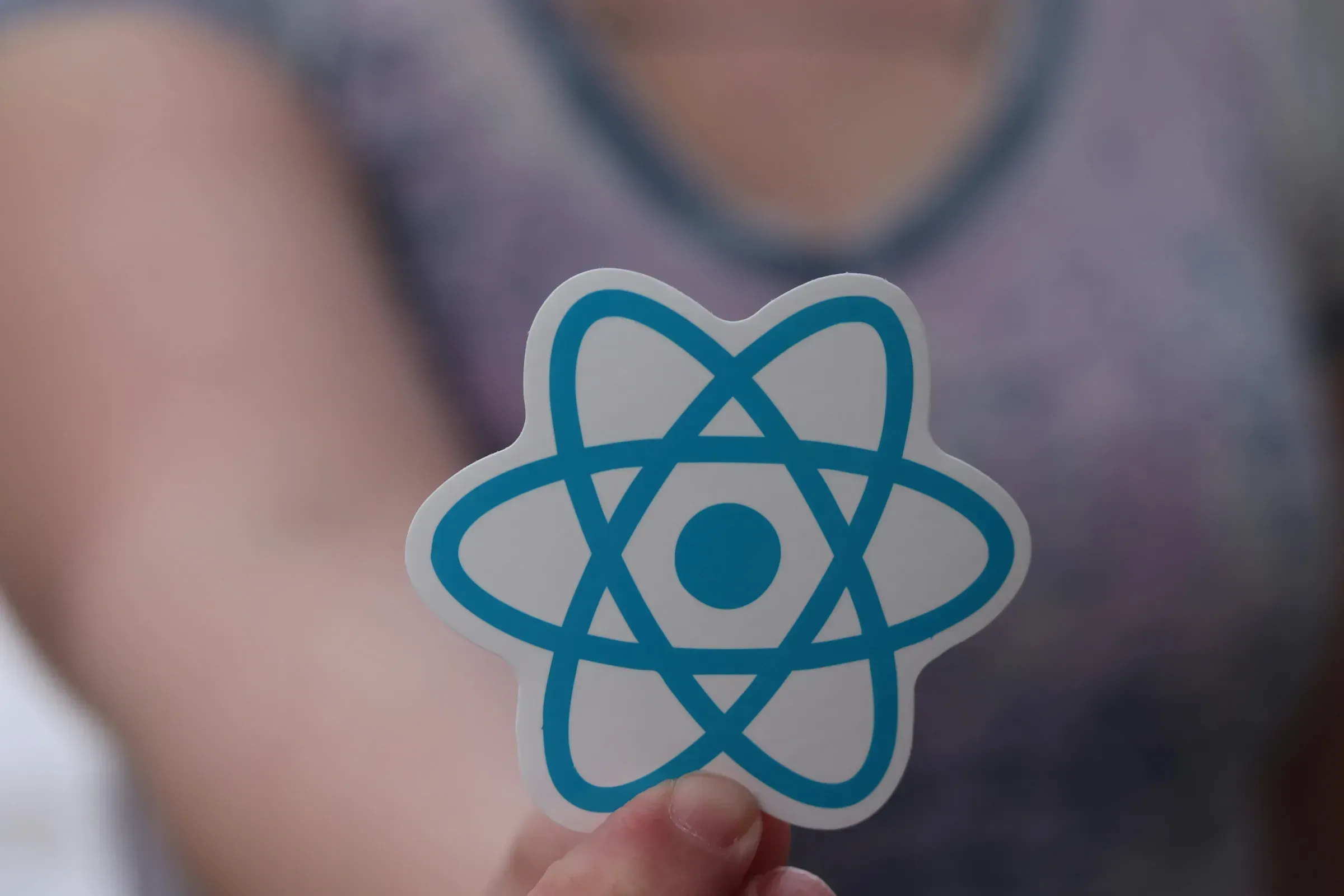 Imagine reprezentativă: react logo in mana unui developer, simbolizând tehnologii moderne ca Astro, React și Next.js.